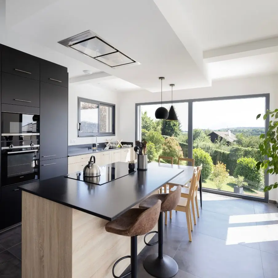 Cuisine contemporaine avec îlot central et grande baie vitrée donnant sur la nature en Haute-Savoie