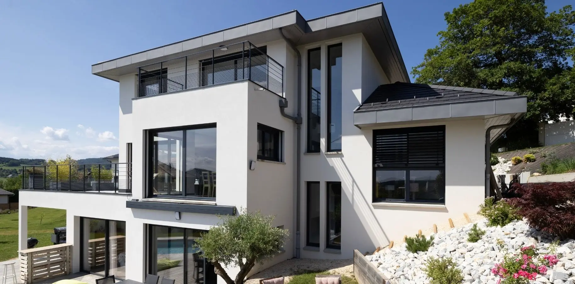 Maison contemporaine à toiture 4 pans avec grandes baies vitrées, construite en Haute-Savoie