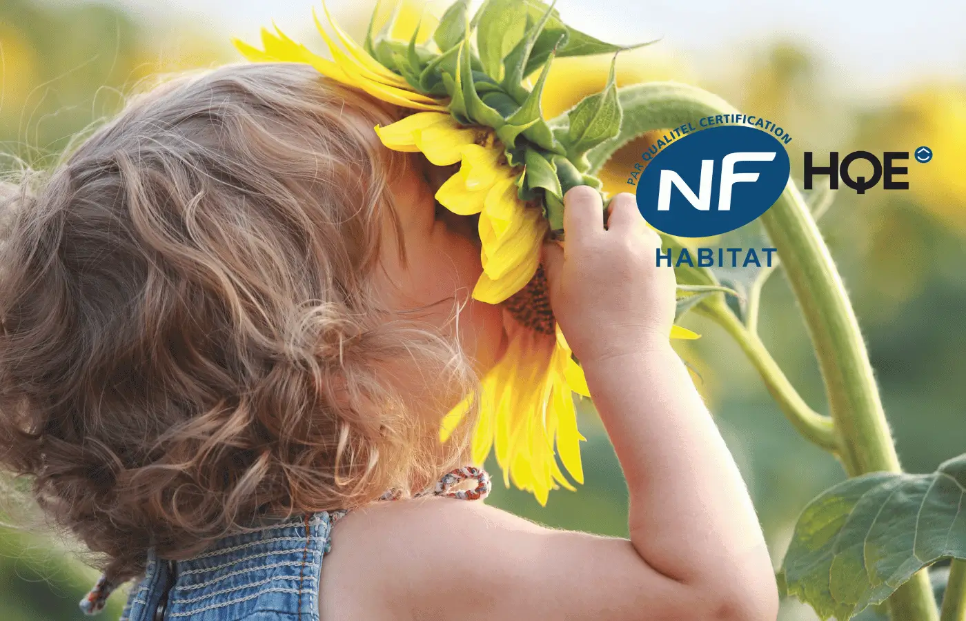 Petite fille sentant un tournesol, symbole d’un habitat sain certifié NF HQE