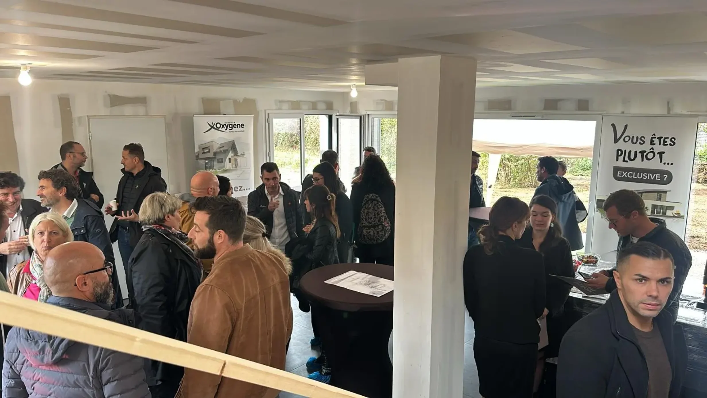 De nombreux visiteurs participent à un échange collectif lors d’une porte ouverte dans un intérieur en finition.