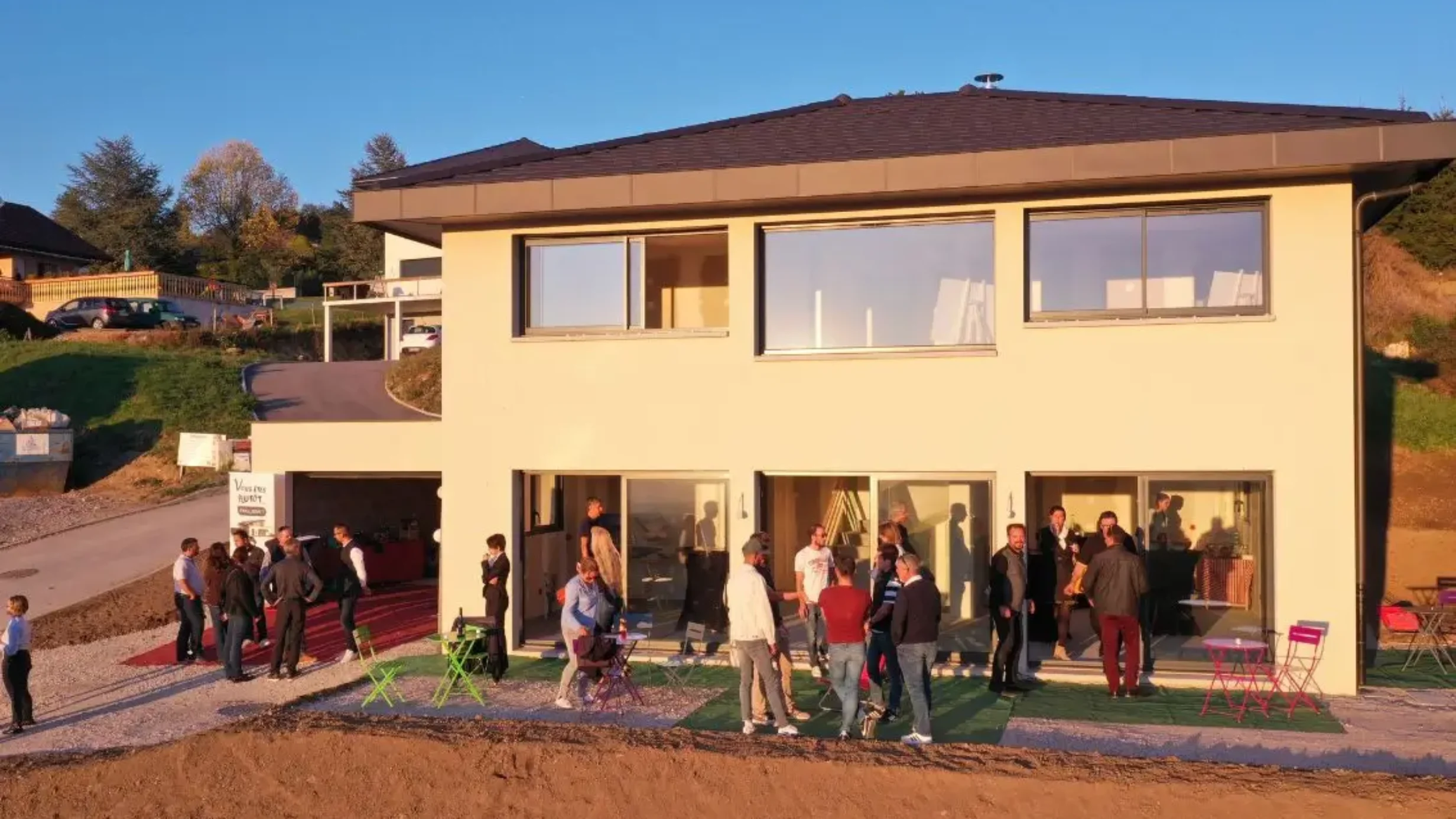 Familles et visiteurs rassemblés devant une maison moderne lors d’une journée portes ouvertes.
