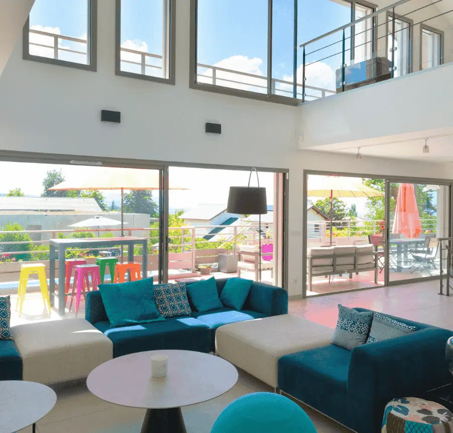 Salon lumineux et coloré avec canapés modernes et accès à une terrasse ensoleillée.