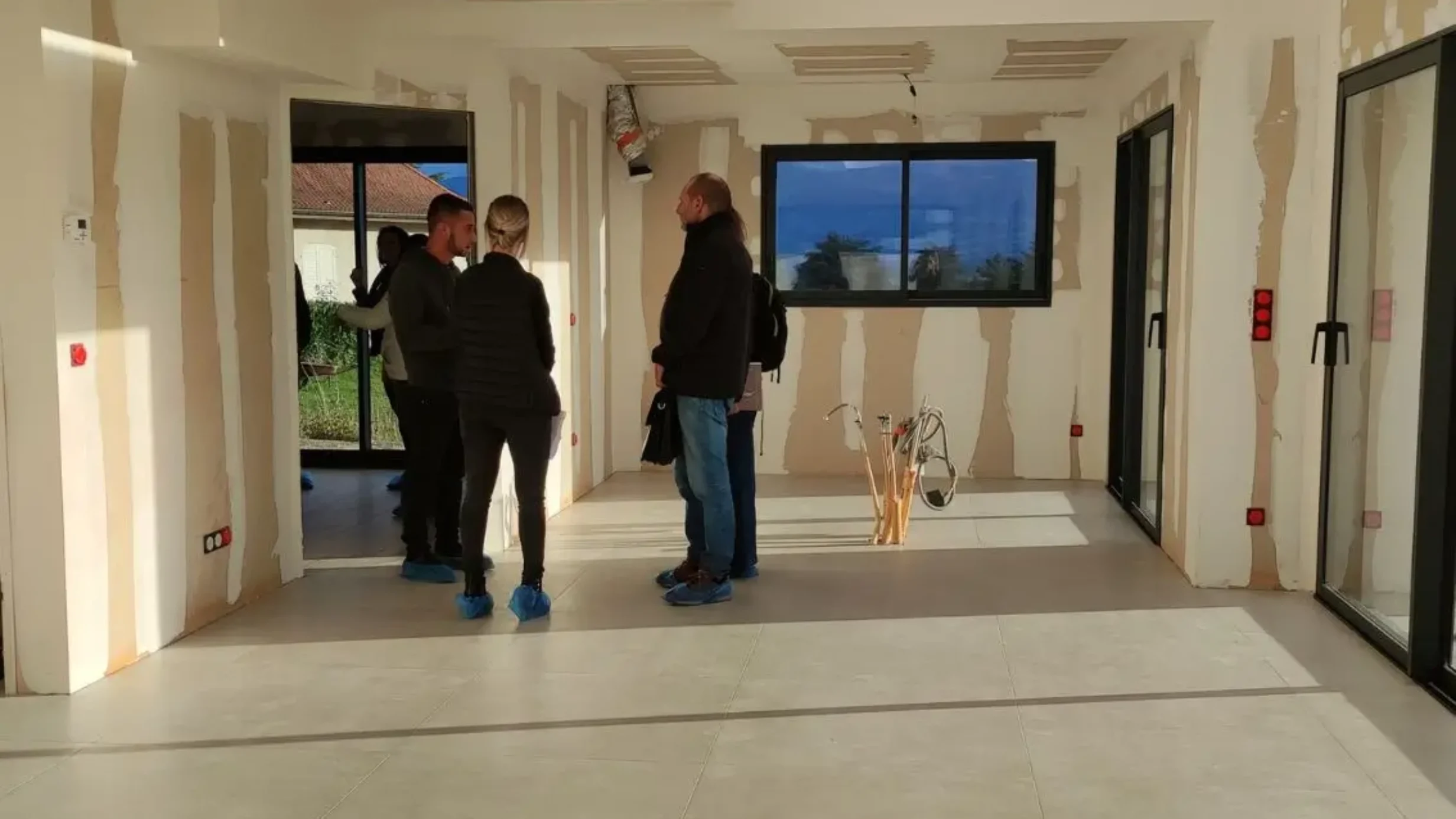 Groupe de prospects discutant lors d'une porte ouverte dans une maison en construction
