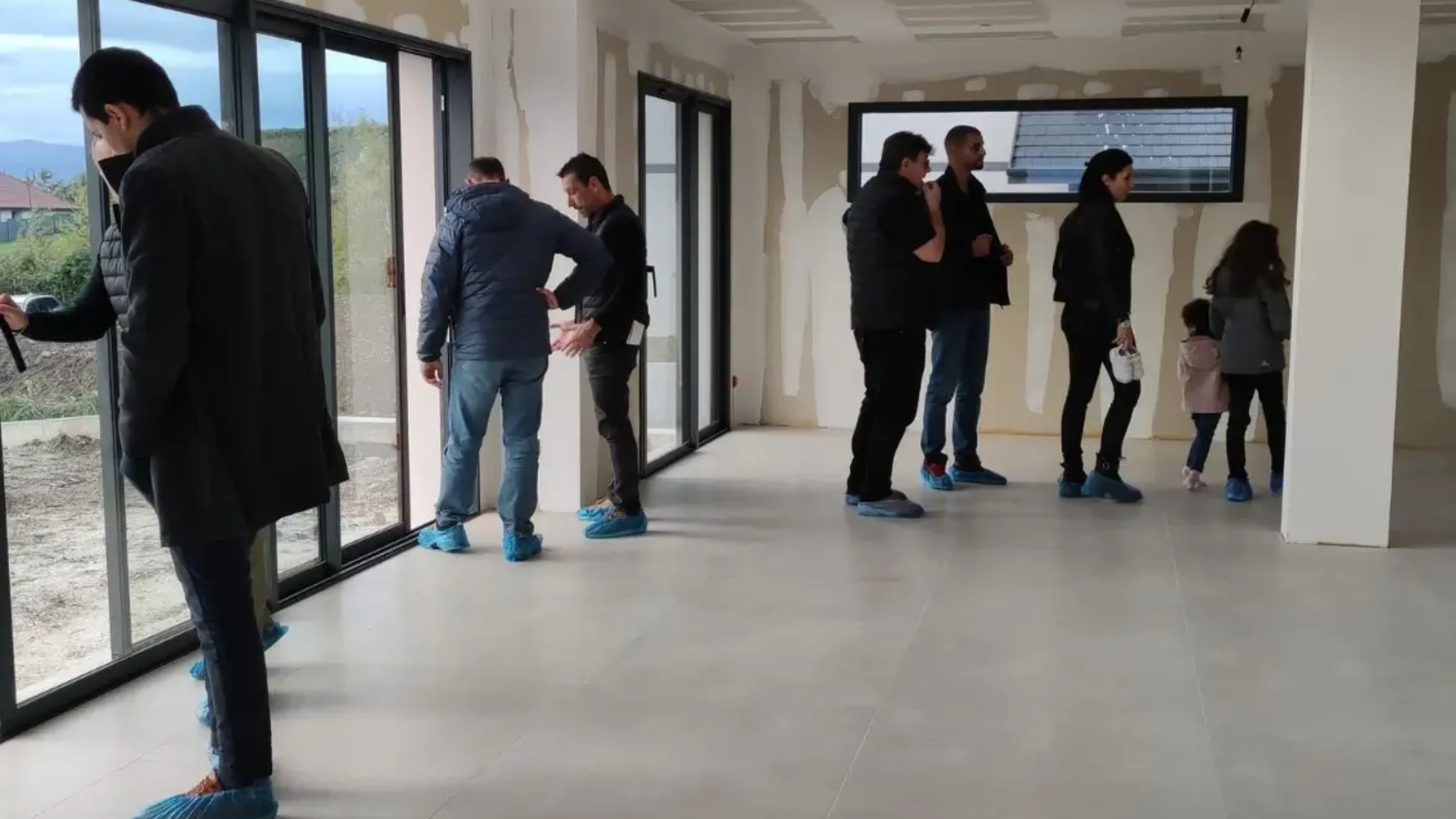 Groupe de visiteurs découvrant les finitions et les volumes d’un logement en cours de livraison.