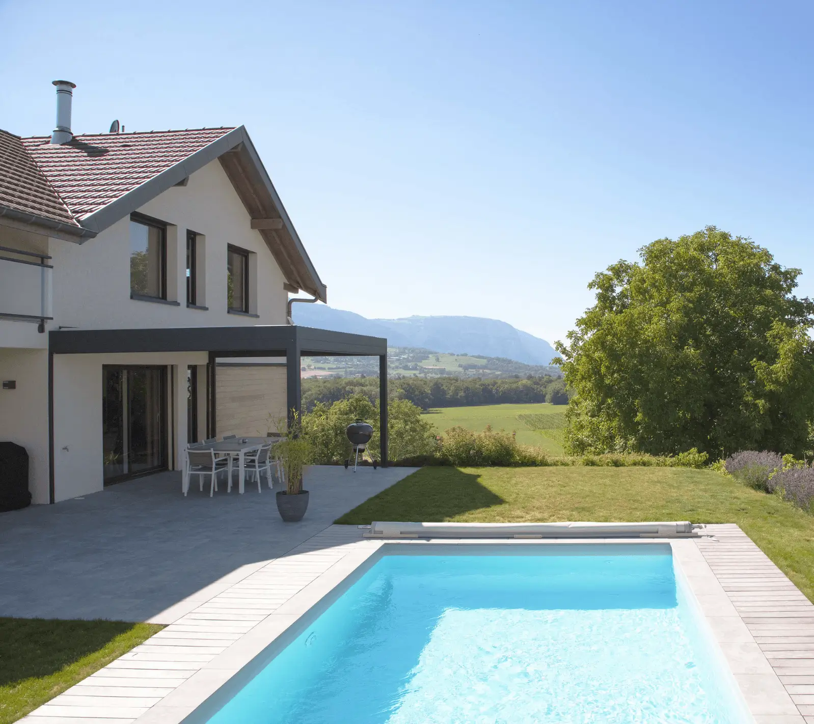 Maison contemporaine avec piscine et terrasse, offrant une vue dégagée sur la campagne.