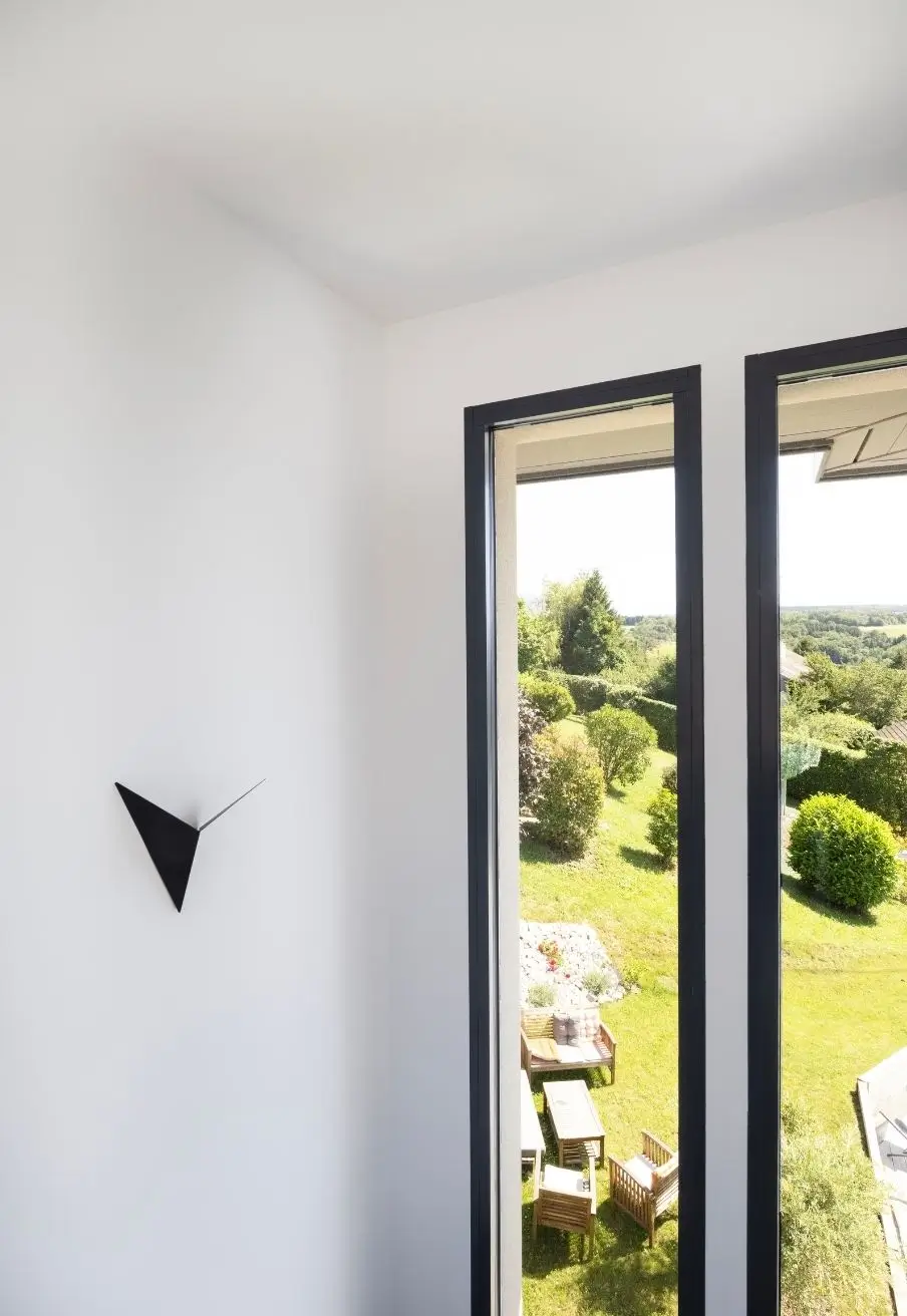Vue sur un jardin arboré depuis une baie vitrée dans un intérieur lumineux
